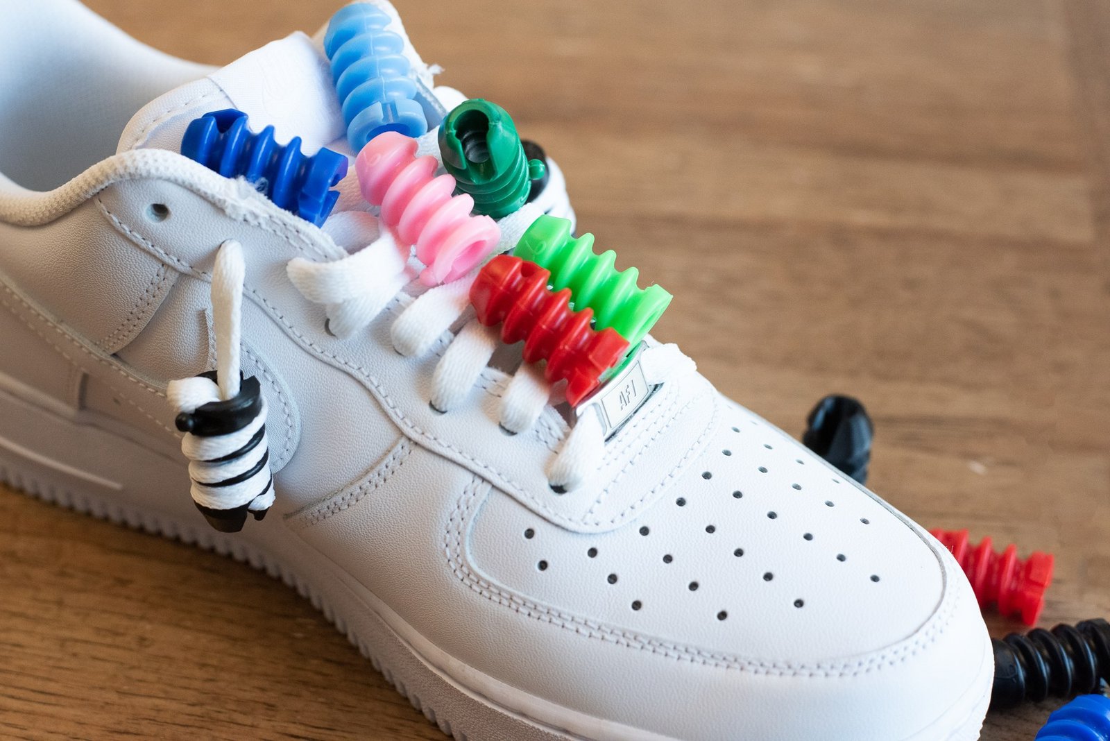 Twirlys G4 twirled across the laces of a white sneaker in blue, pink, green and red